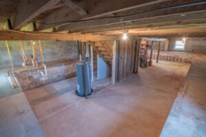 Open crawl space with timber floor joists, concrete walls and plumbing in Concord NC
